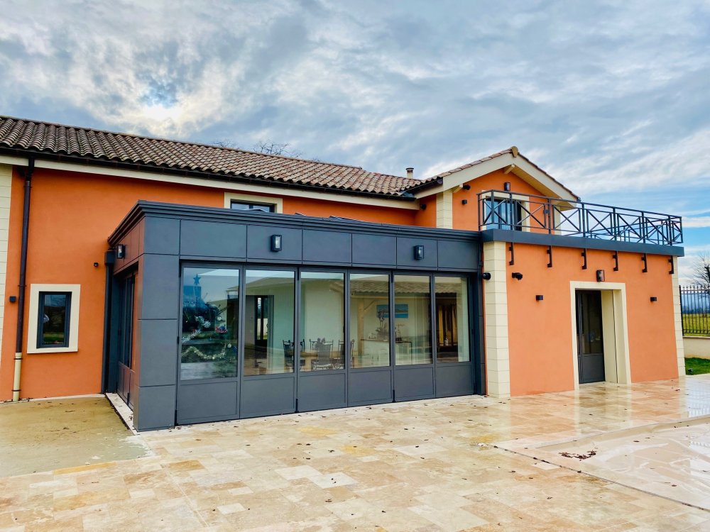 ? Rénovation et extension d’une habitation d’exception près de Villefranche-sur-Saône (69), intégrant des baies accordéon, une toiture vitrée et des stores sur-mesure.