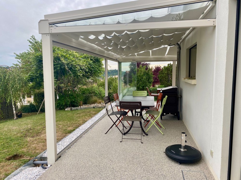 Installation d’une toiture vitrée sur-mesure et de coulissants pivotants : élégance et transparence pour une charmante maison dans l’Ain (01)