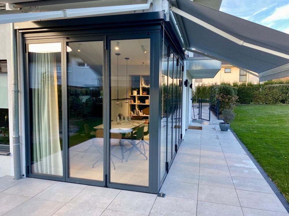 Splendide extension de pièce de vie réalisée grâce à une baie accordéon d’angle, offrant une ouverture maximale sur l’extérieur.