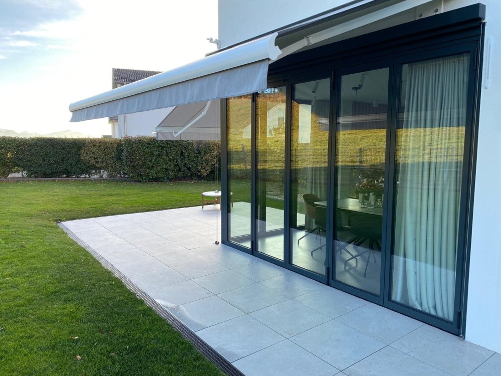 Splendide extension de pièce de vie réalisée grâce à une baie accordéon d’angle, offrant une ouverture maximale sur l’extérieur.