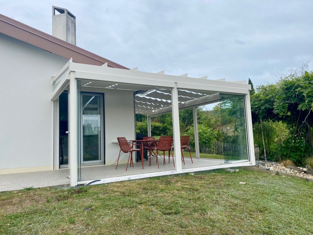 Installation d’une toiture vitrée sur-mesure et de coulissants pivotants : élégance et transparence pour une charmante maison dans l’Ain (01)