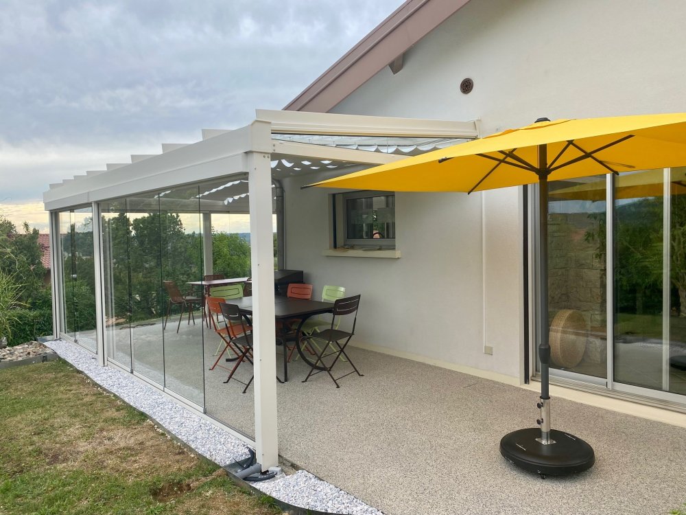 Installation d’une toiture vitrée sur-mesure et de coulissants pivotants : élégance et transparence pour une charmante maison dans l’Ain (01)