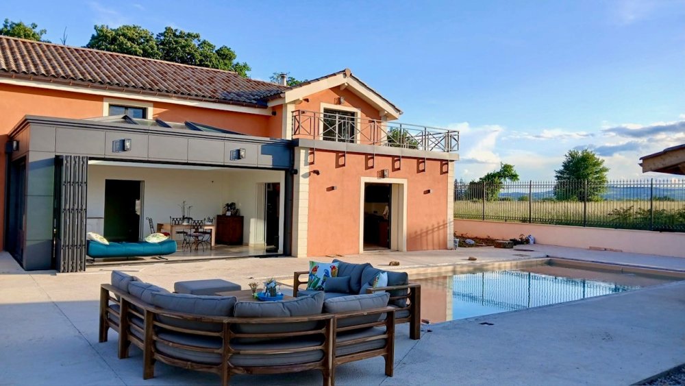 Rénovation et extension d’une habitation d’exception près de Villefranche-sur-Saône (69), intégrant des baies accordéon, une toiture vitrée et des stores sur-mesure.