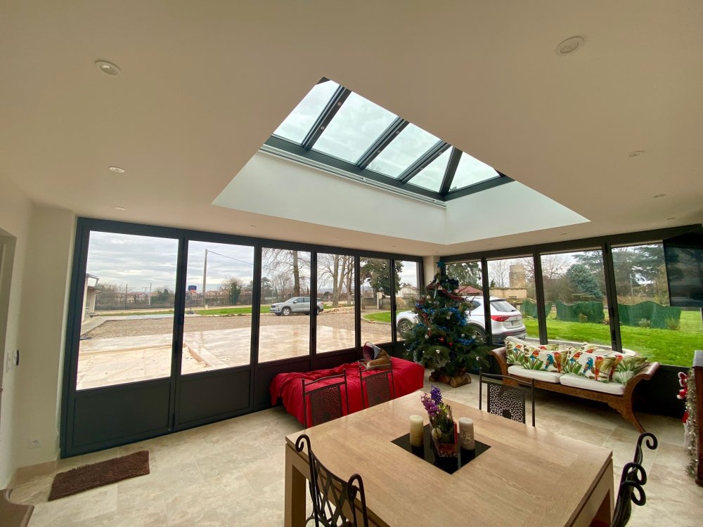 Rénovation et extension d’une habitation d’exception près de Villefranche-sur-Saône (69), intégrant des baies accordéon, une toiture vitrée et des stores sur-mesure.
