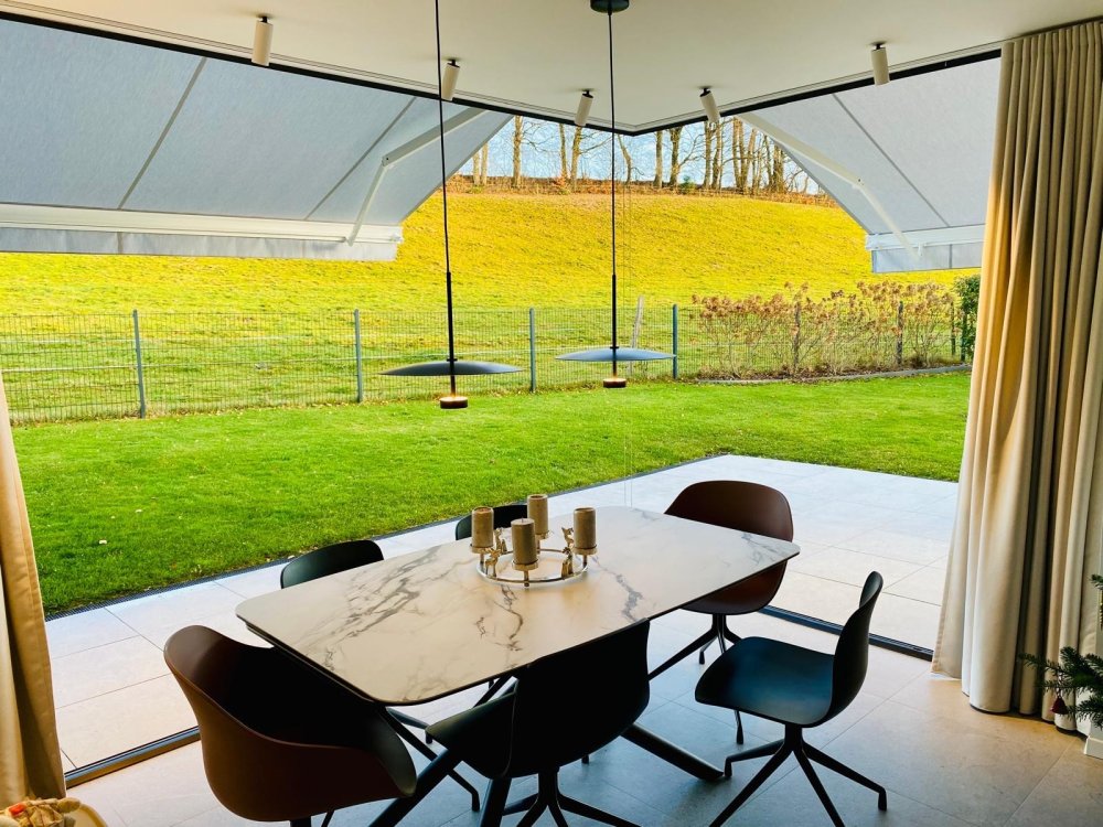 Splendide extension de pièce de vie réalisée grâce à une baie accordéon d’angle, offrant une ouverture maximale sur l’extérieur.