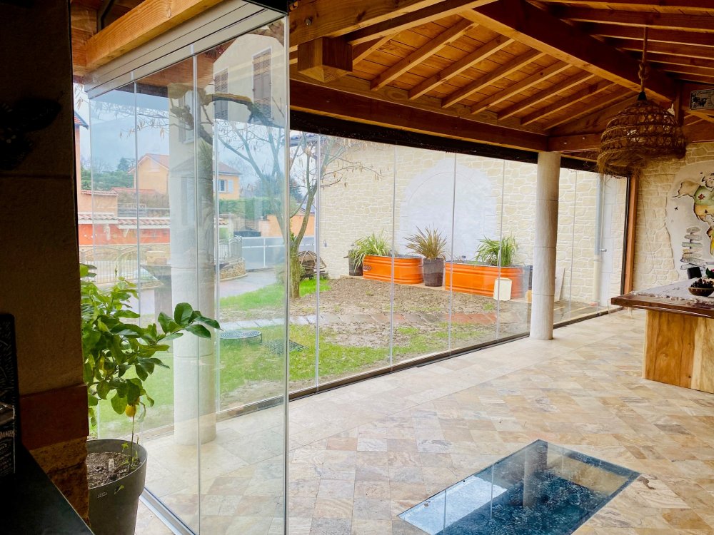 Conception et installation d’un système de fermeture de terrasse sur-mesure, harmonieusement intégré à cette habitation située dans l’Ain (01)