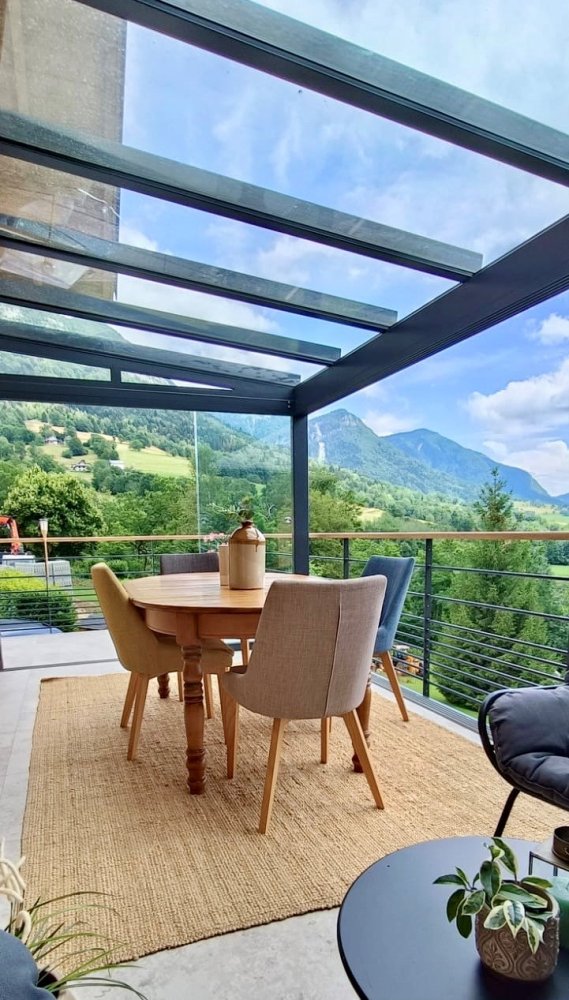 Fourniture et pose d'une pergola vitrée équipée de coulissants pour profiter d'une vue époustouflante sur la région Haute-Savoie.