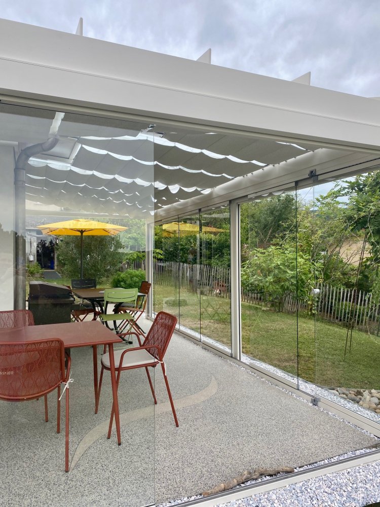 Installation d’une toiture vitrée sur-mesure et de coulissants pivotants : élégance et transparence pour une charmante maison dans l’Ain (01)